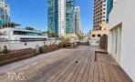 מרפסת עץ נוספת עם אדניות ושולחן עץ מול מגדלי זכוכית במשרד להשכרה בתל אביב