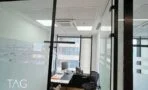 מבט דרך דלת הזכוכית אל חדר עם כיסא רשת שחור, תקרה אקוסטית ומזגן מובנה, משרד 73 מ